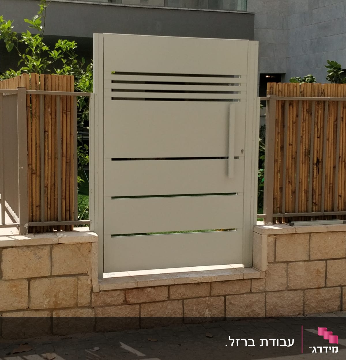 שער מתכת לבן עם פסים אופקיים, מוקף בגדר במבוק.